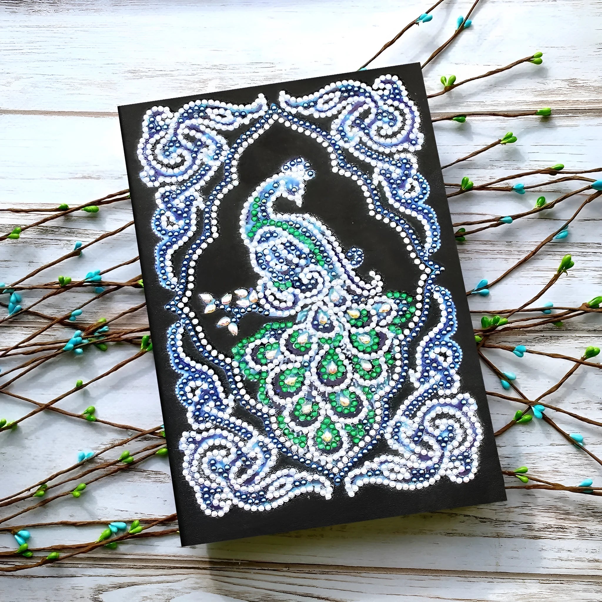 Black A5 diamond painting notebook with shaped and bright rhinestone designs on the cover.
