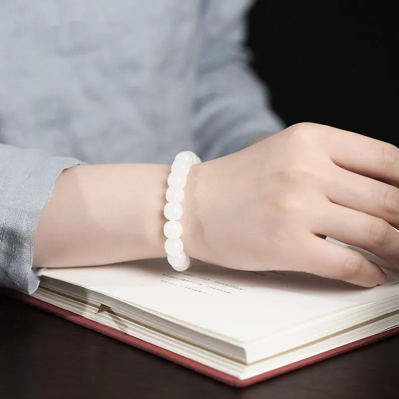 White Hetian jade barrel bead bracelet on a wrist, showing three bead size options.