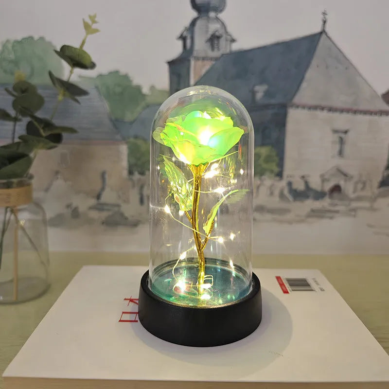 Small decorative night lamp with glass cover and plastic flowers, showing coloured light illumination.