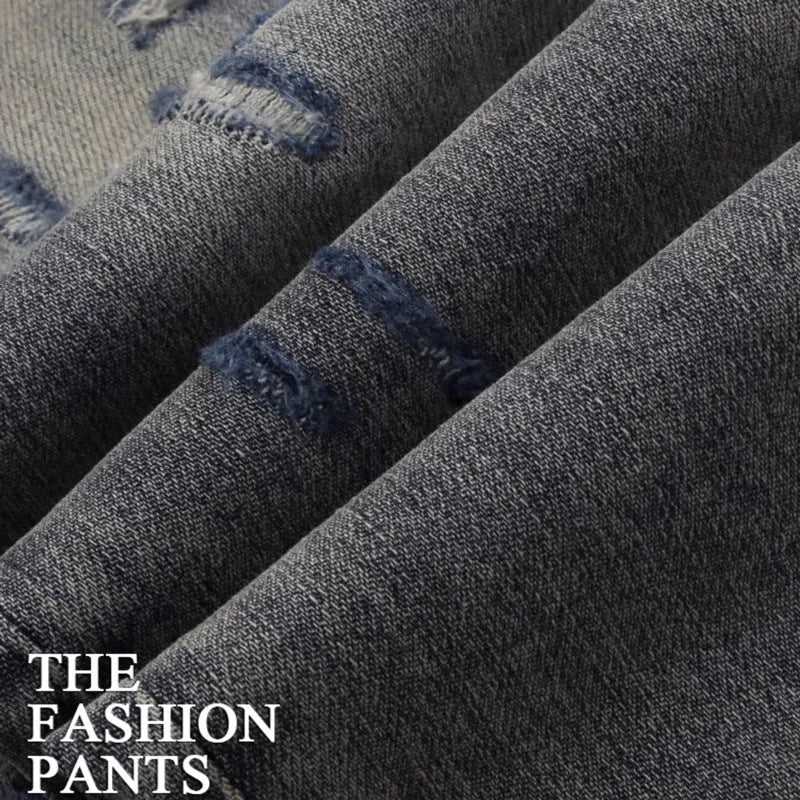 Men's blue slim fit jeans with distressed holes and embroidered patches on faded denim.