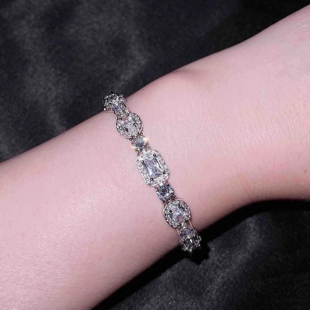 Women's geometric silver and white gold plated bracelet with inlaid zircon stones on a model's wrist.