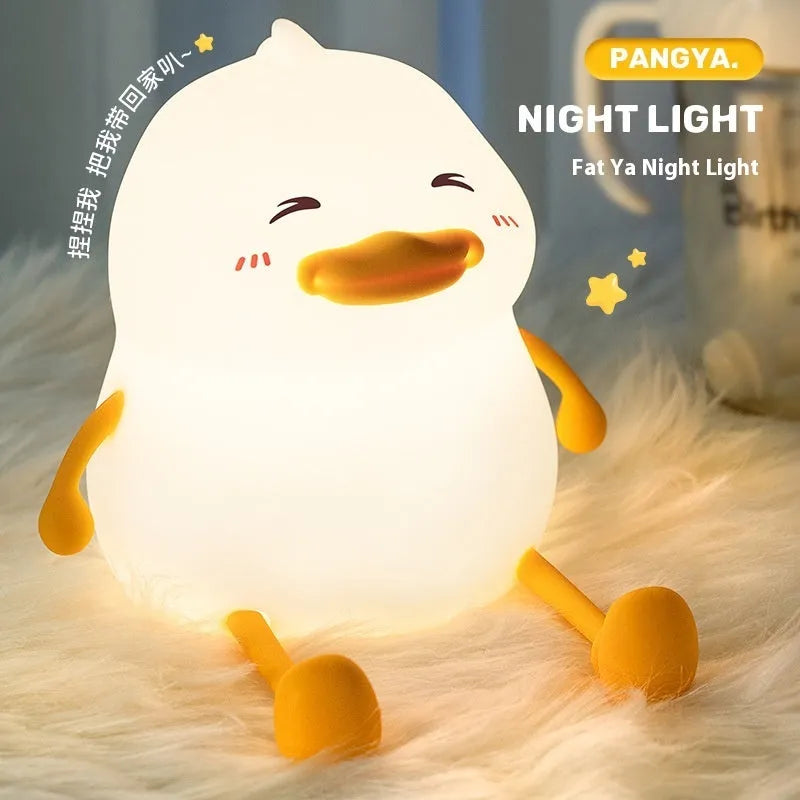 Chubby silicone night light lamp with phone holder on desk, showing soft LED glow and compact 108x104x128mm dimensions
