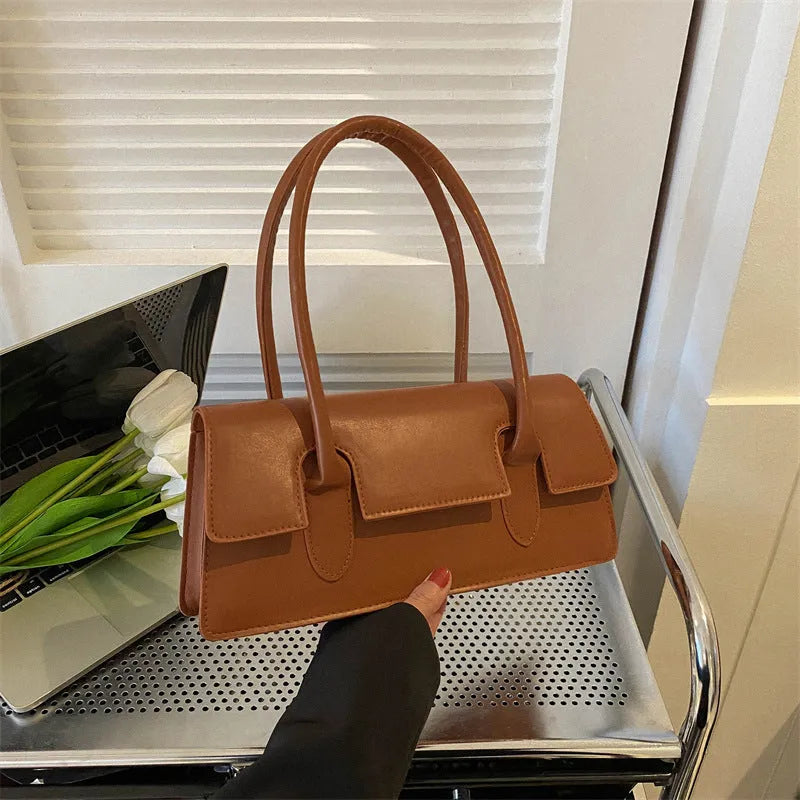 Women's black PU leather small square shoulder bag with stitching detail on a table.