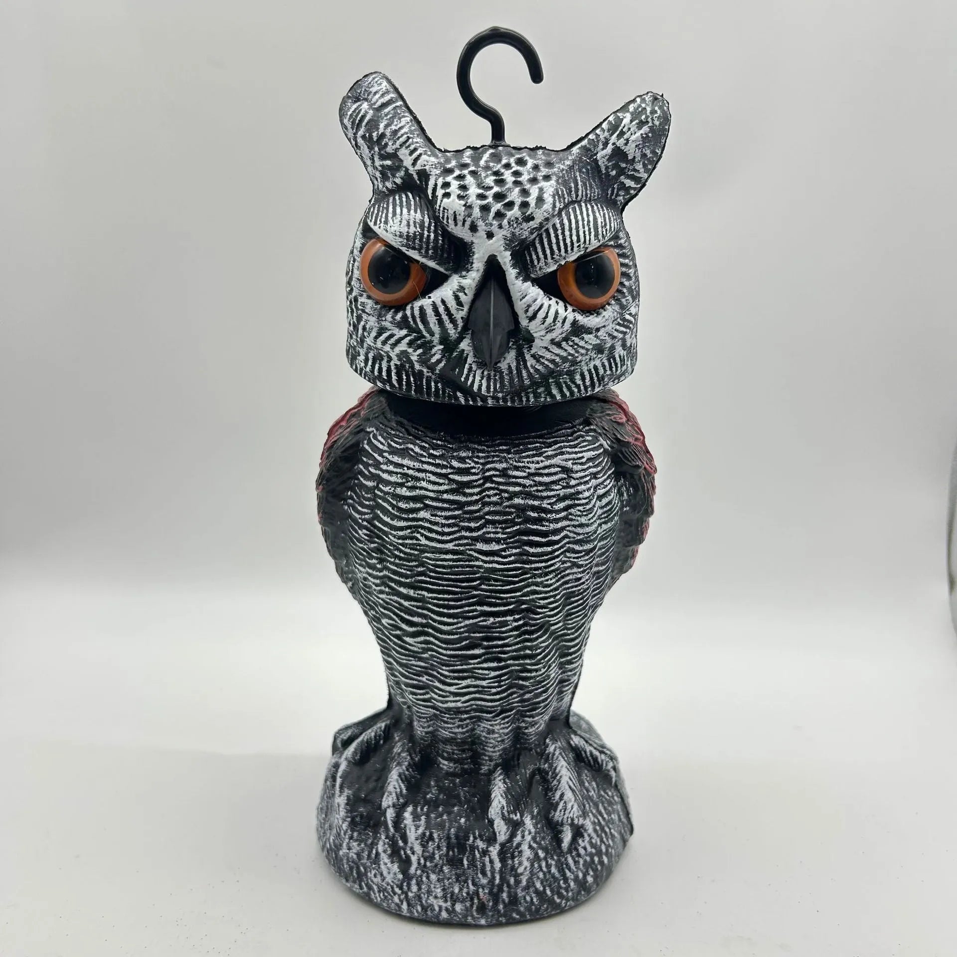 Polyethylene artificial owl bird scarer ornament with moving head, shown in a garden setting.