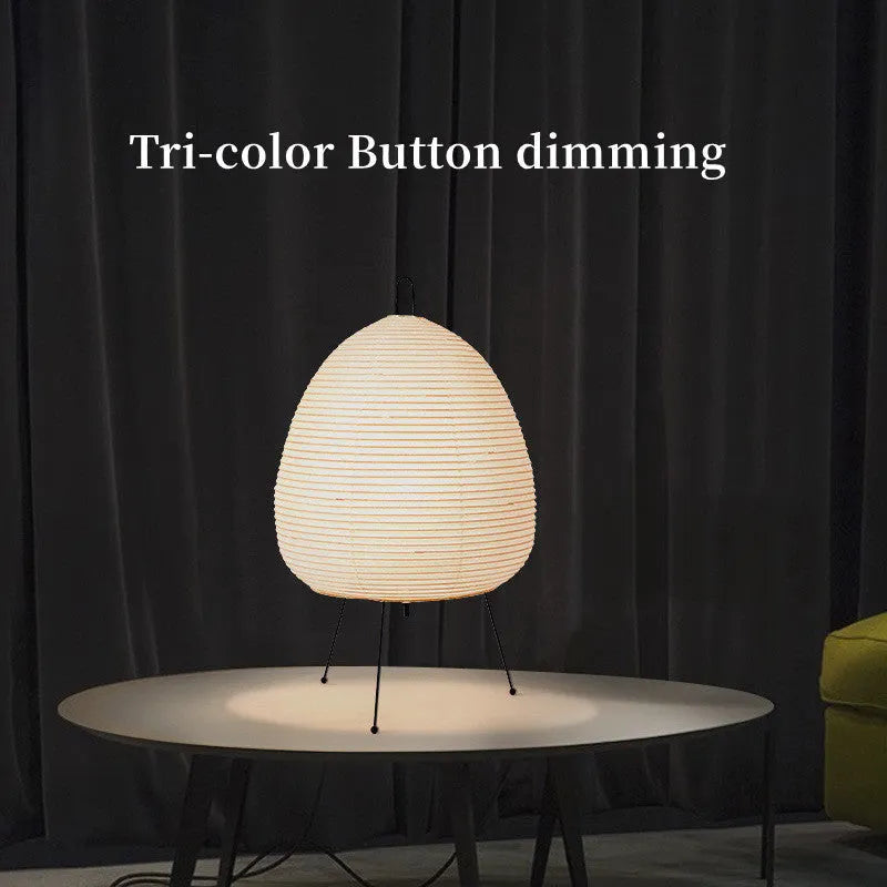 Japanese style table lamp with a white rice paper lantern shade and a silver aluminium base on a wooden table.