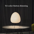 Japanese style table lamp with a white rice paper lantern shade and a silver aluminium base on a wooden table.