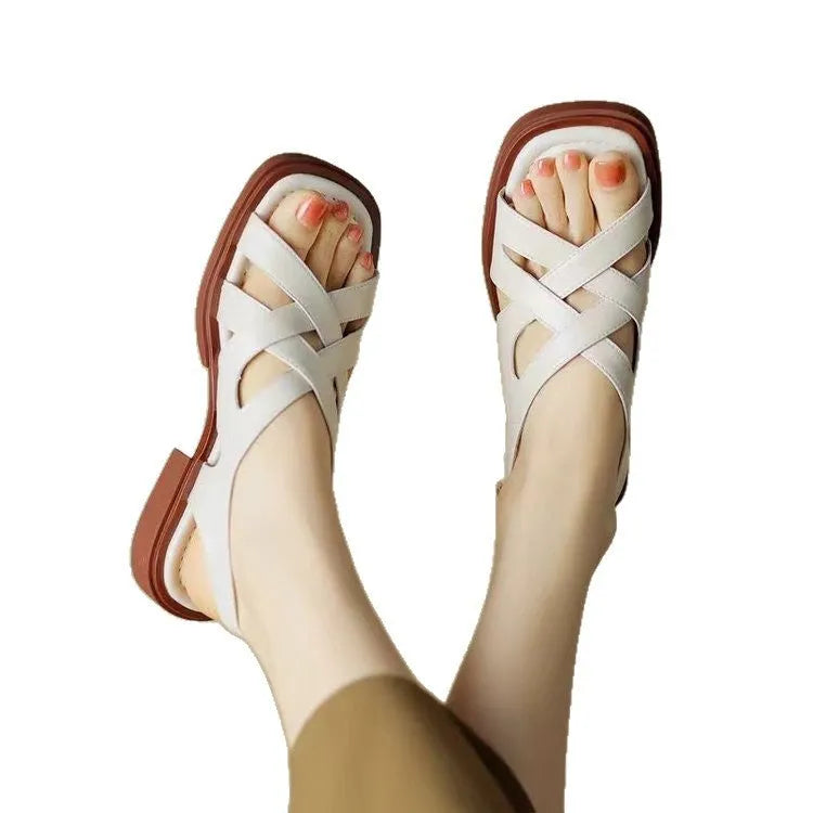Glossy black patent leather women's sandals with a square toe and cross strap design.