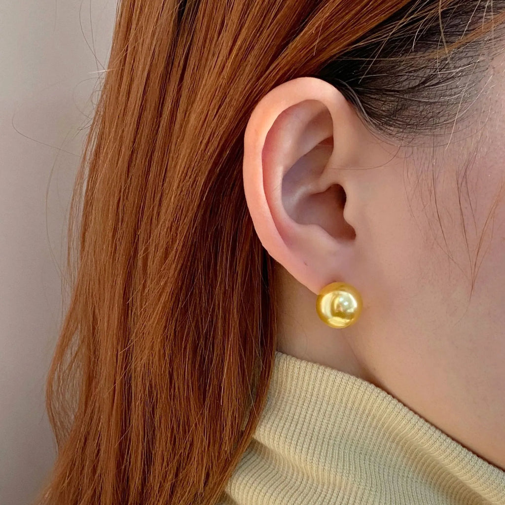 A pair of large pearl stud earrings with a geometric silver setting and an eight-awh star detail on a white background.