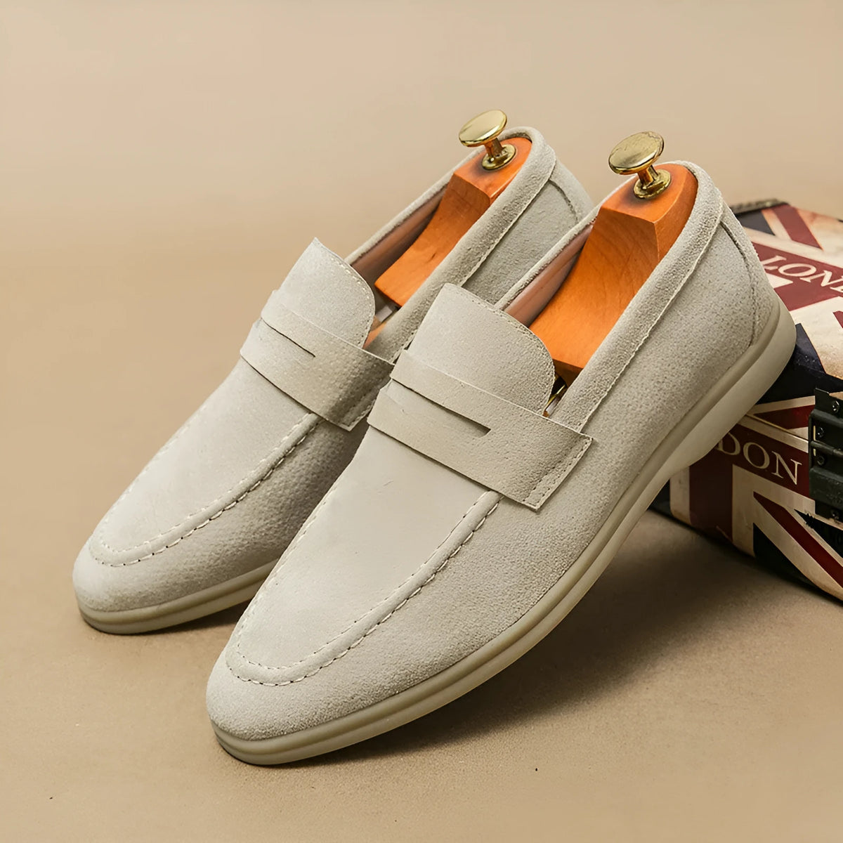 Men's beige leather slip-on casual shoes with a round toe and rubber sole on a neutral background.