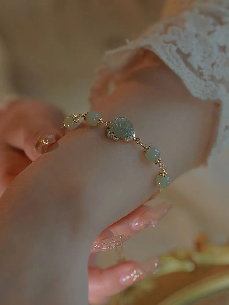 Original design women's bracelet with a Hetian Jade rose and 14K gilded details on a wrist.