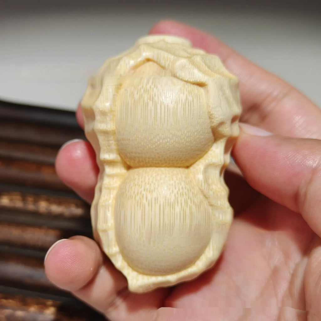 Solid bamboo peanut-shaped ornament with natural wood grain on wooden surface