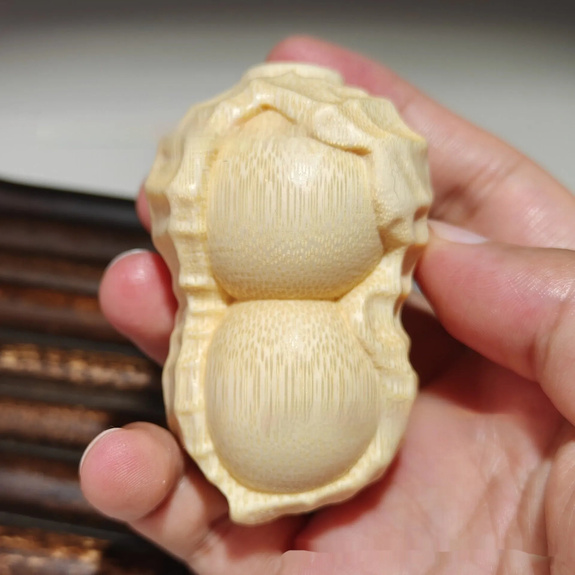 Solid bamboo peanut-shaped ornament with natural wood grain on wooden surface