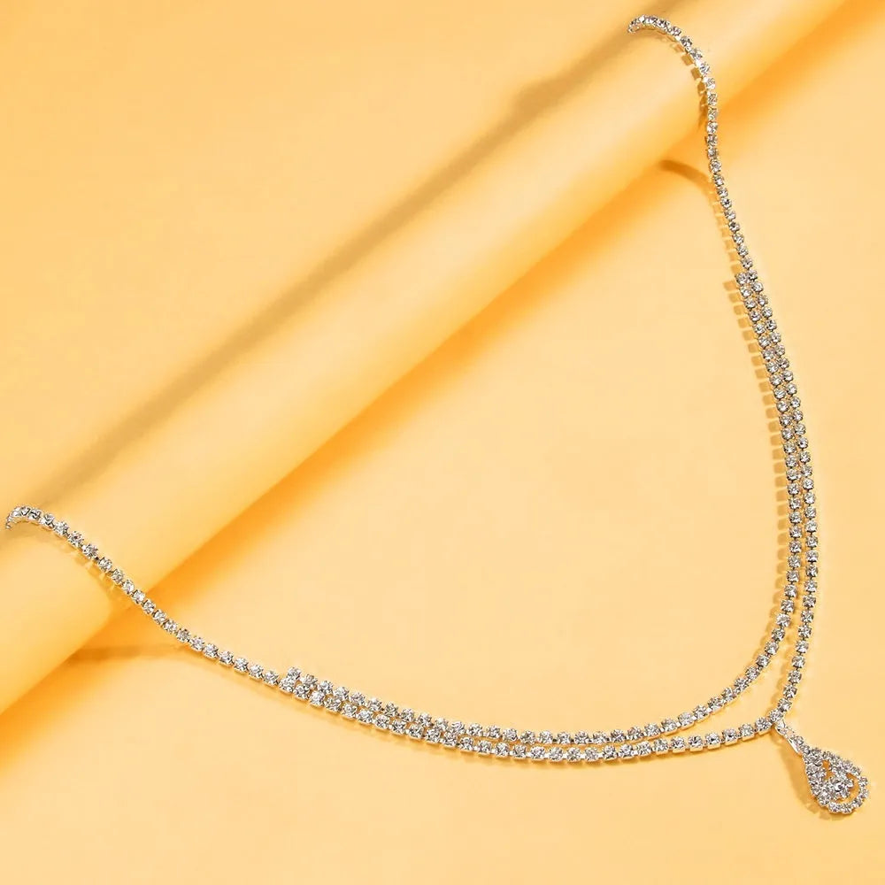Gold or silver rhinestone waist chain with water drop pendant and tassel elements, showing lobster clasp closure