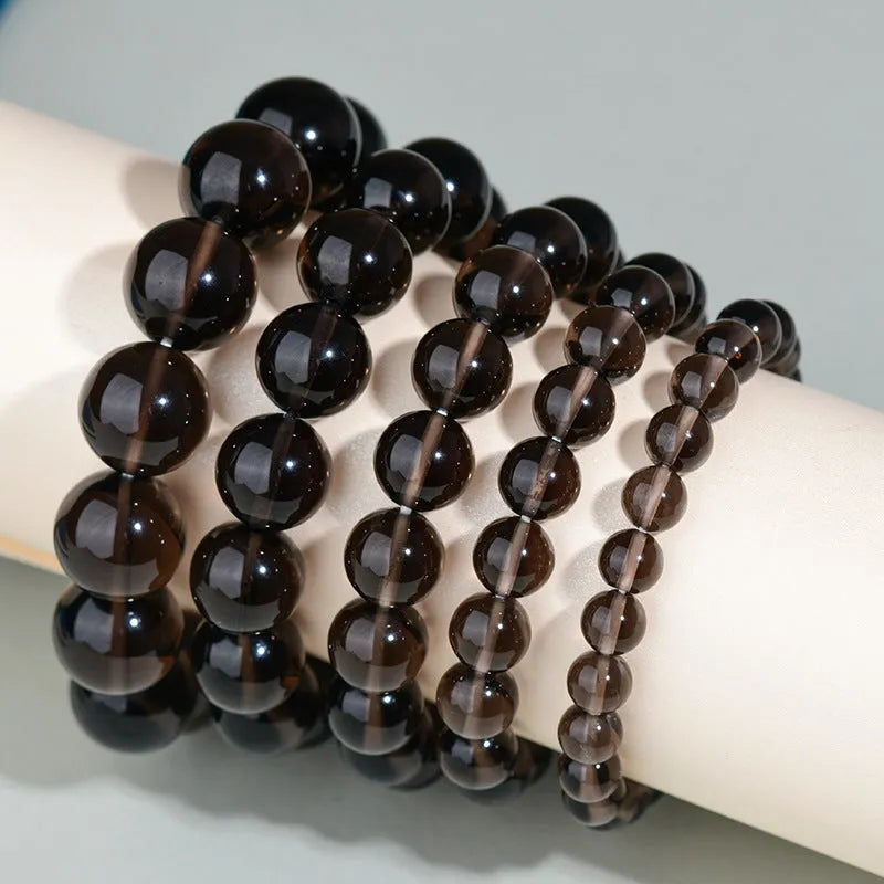 Hand-woven round obsidian bracelet in black stone, shown on a wrist.