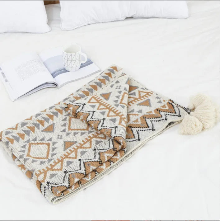 Acrylic sofa blanket with tassel fringe in neutral beige tone on grey sofa