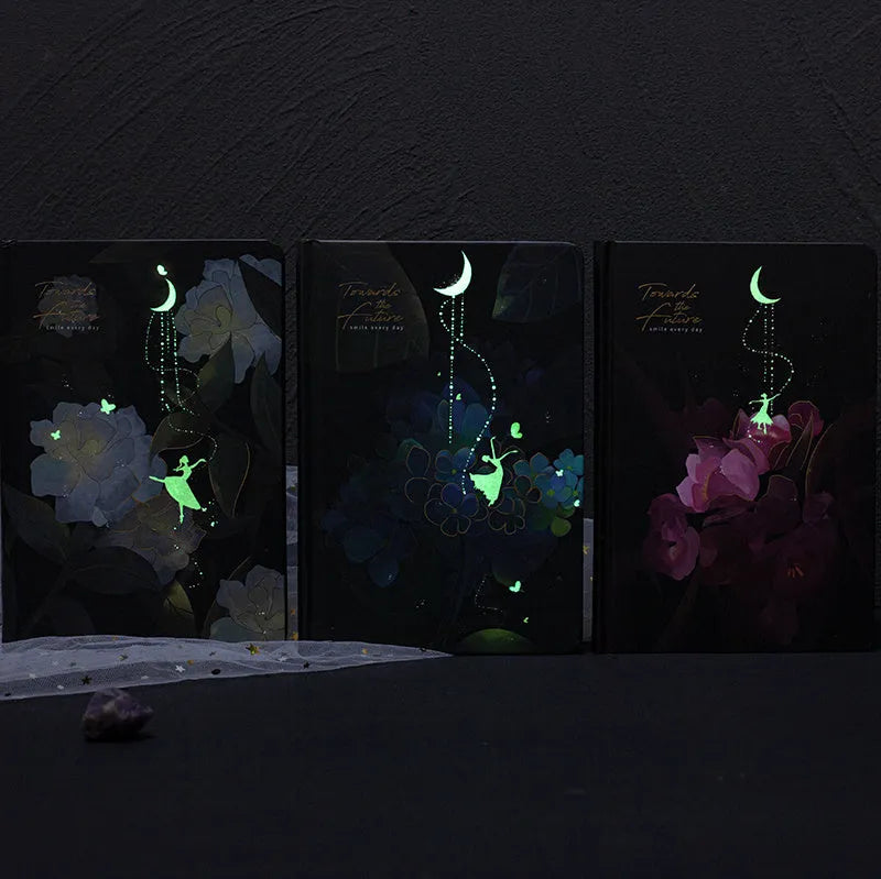 A5 notebook with luminous cover open to show colour illustrated pages, available in four colours.