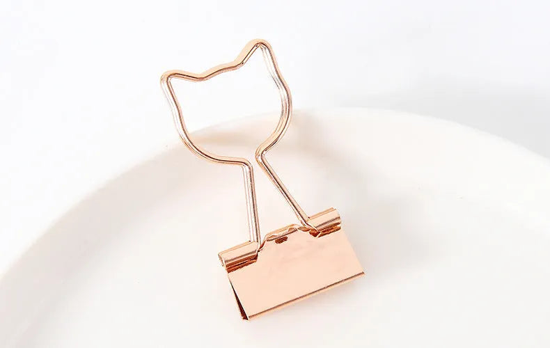 Gold plated decorative paper clip in a choice of flamingo, love, cloud, cat, cactus, or bow designs on a white background.