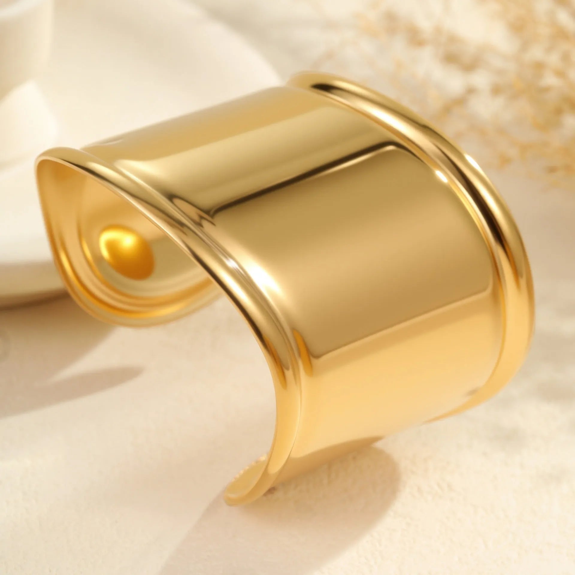 Gold-plated stainless steel wide bracelet with wave geometric design and a niche opening.