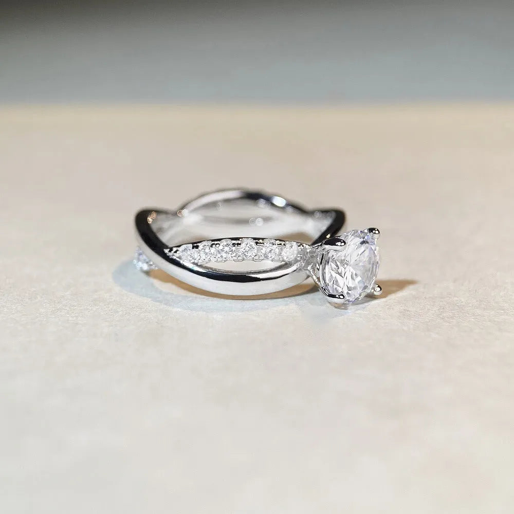 Women's geometric cross moissanite ring with twisted silver band and 1 carat stone.