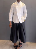 White asymmetric long sleeve shirt paired with black pleated pants in casual two-piece set