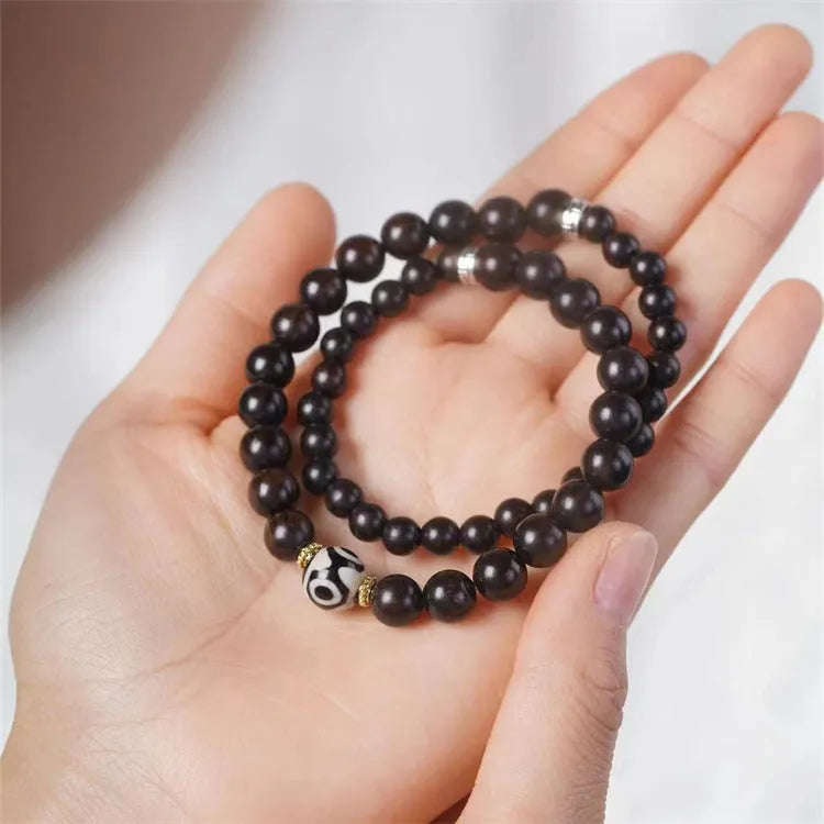 Dark ebony wood bracelet with 8mm beads in a two-circle Tibetan style on a wrist.
