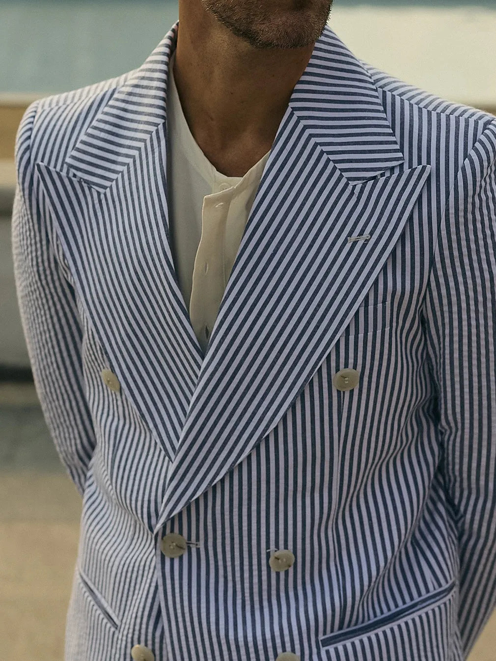 Blue and white striped polyester suit set with blazer and trousers on a hanger