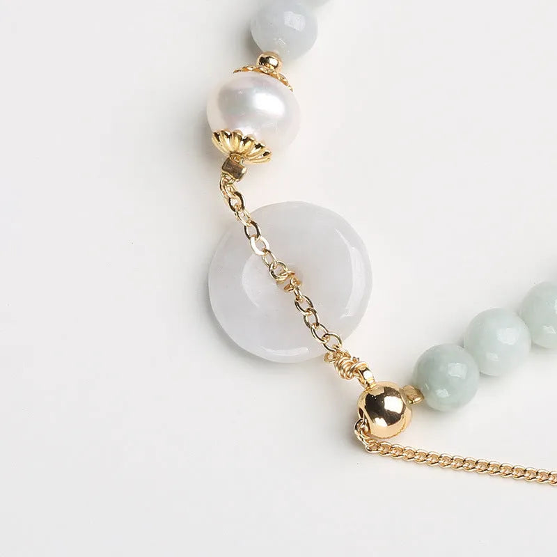 Natural emerald jade bracelet with pearl elements and peace buckle charm on adjustable cord
