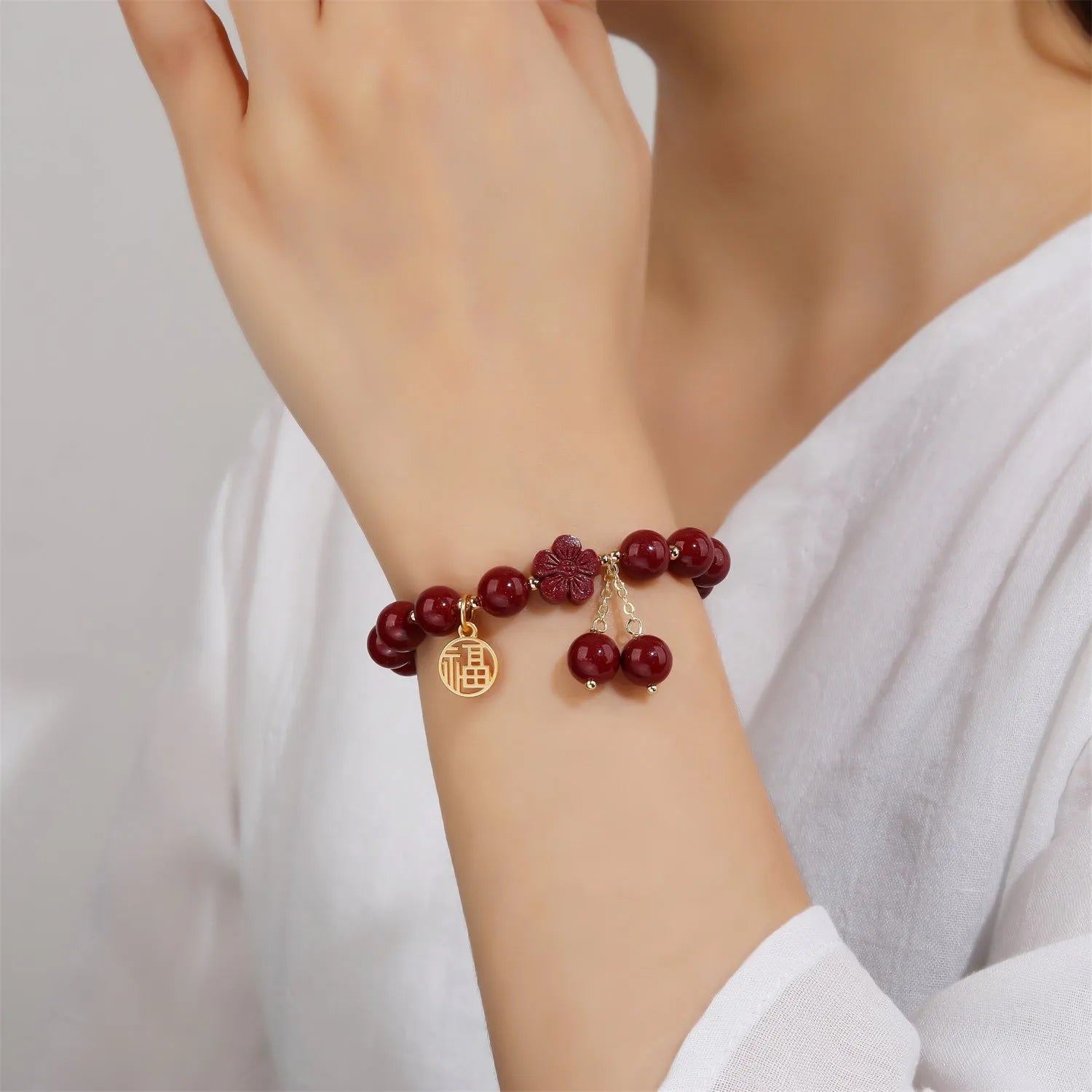 Women's cinnabar bracelet with purple gold sand finish and traditional fu character charm with tassel detailing