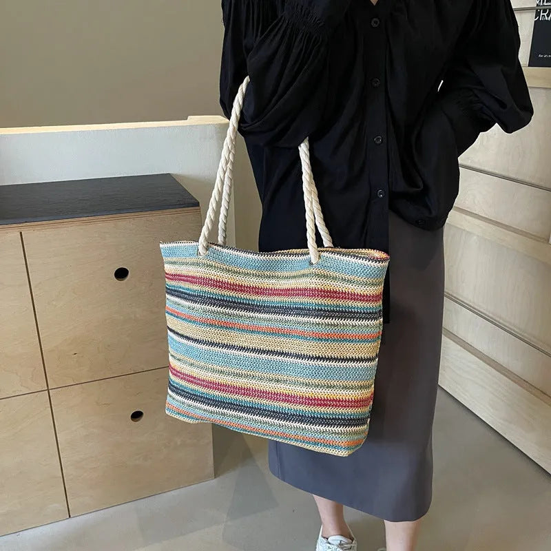 Blue woven straw and nylon shoulder bag with a large main compartment and zippered closure.