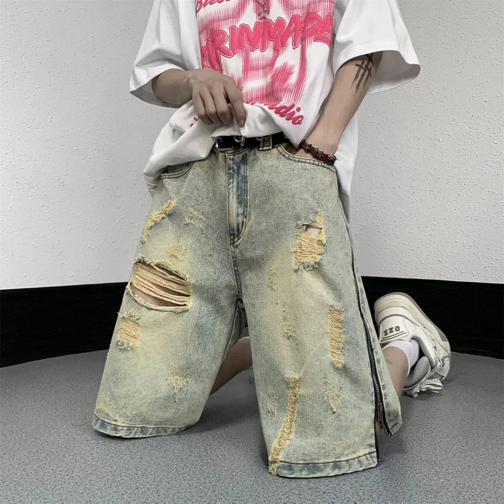 Man wearing blue ripped denim shorts with a yellow mud wash and button-fly closure