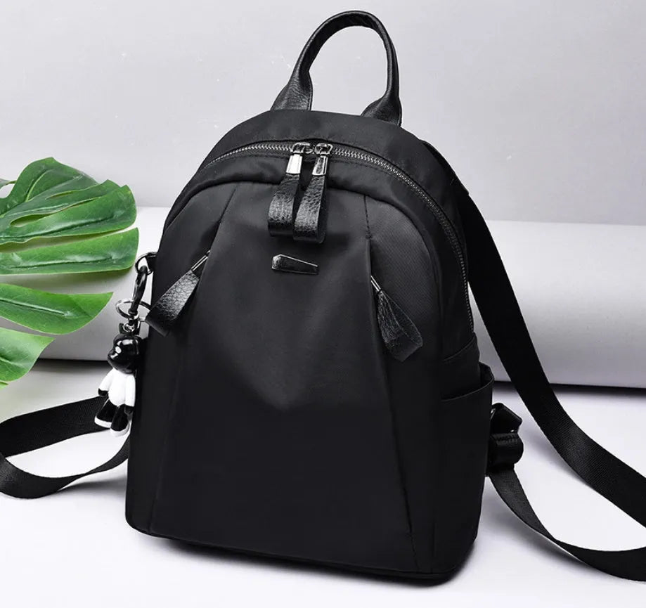 Medium square grey Oxford cloth rucksack with double straps, shown open to reveal internal phone and organiser pockets.