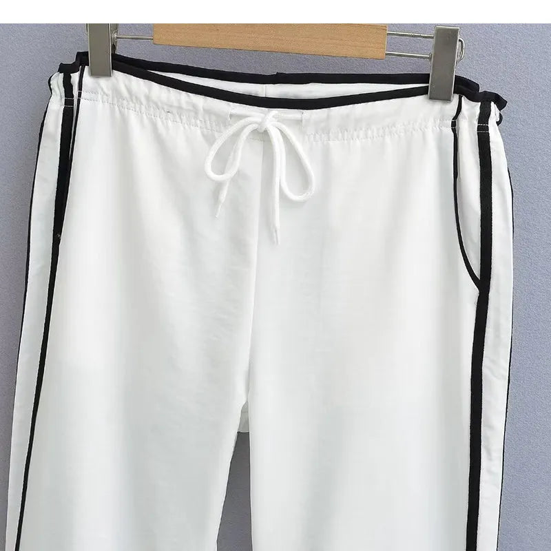 Women's navy blue loose straight-leg trousers with white contrast ribbon detail on parallel bars, low waist, draping silhouette