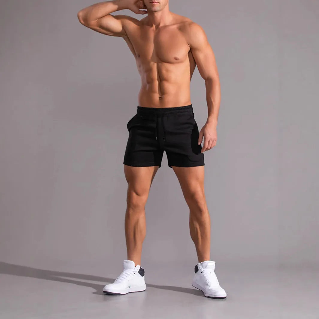 Three men's drawstring shorts in black, khaki, and light brown laid flat, showing loose fit and elasticated fabric.