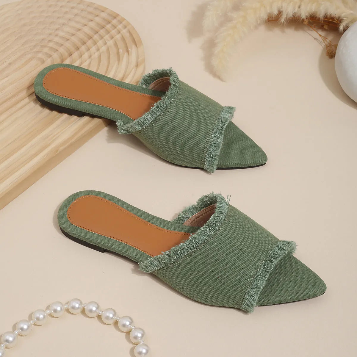 Women's flat denim slippers with tassel detail in apricot colour on a white background.
