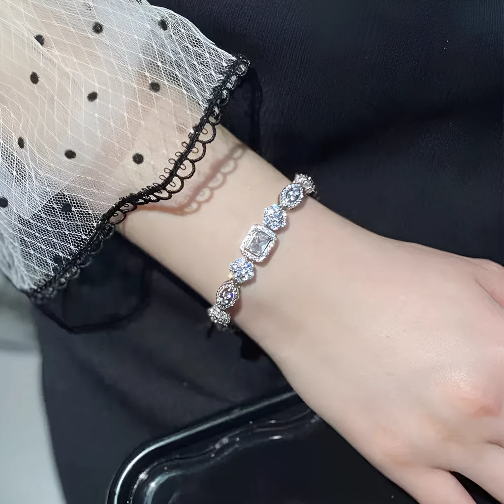 Women's geometric silver and white gold plated bracelet with inlaid zircon stones on a model's wrist.