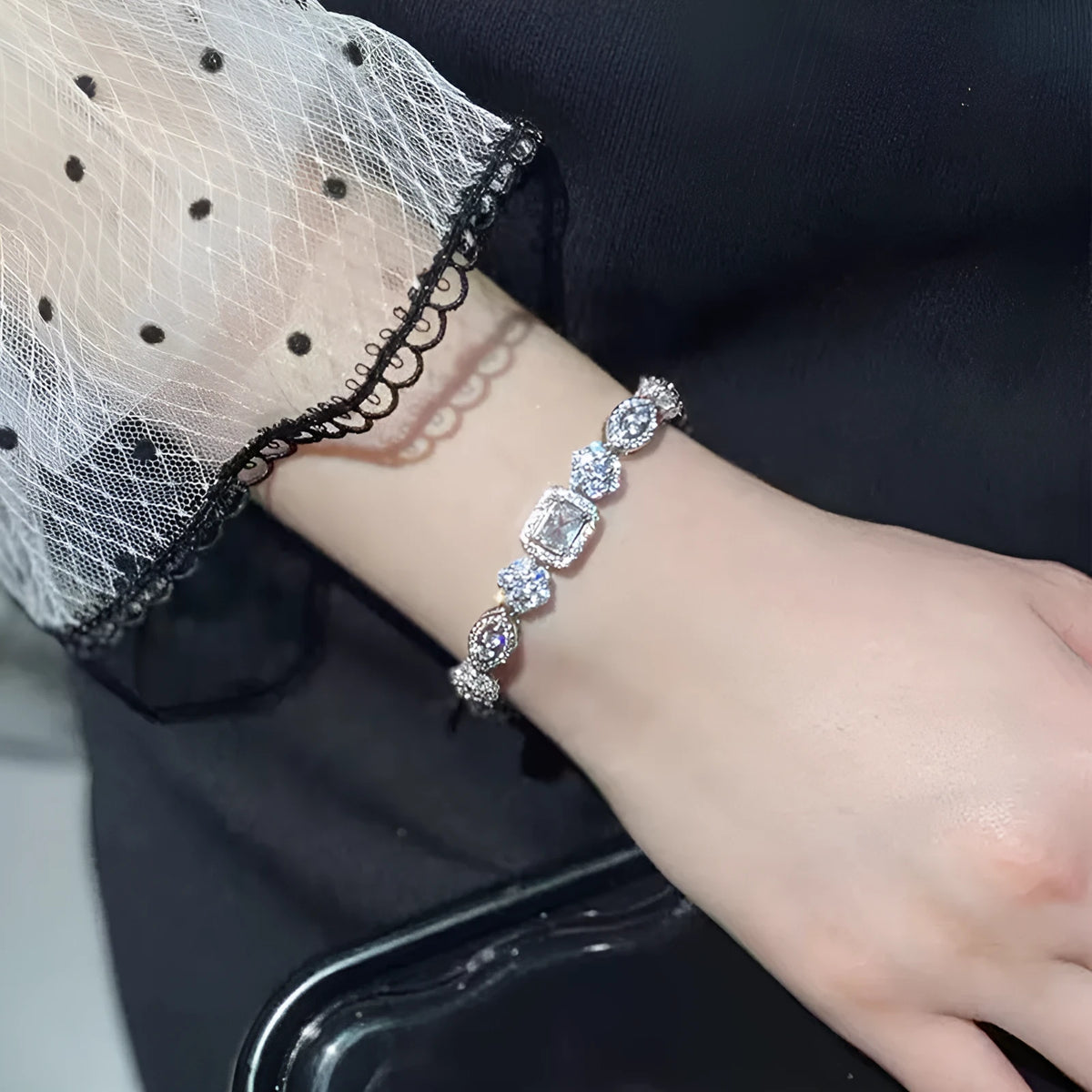 Women's geometric silver and white gold plated bracelet with inlaid zircon stones on a model's wrist.