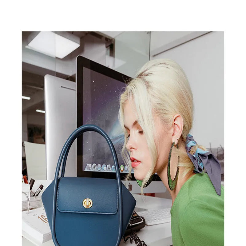 A wing-shaped women's leather tote bag with a buckle latch, shown in blue with a cross-body strap.