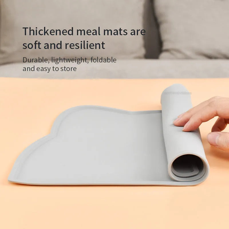 Blue silicone pet feeding mat with cat head shape under food and water bowls