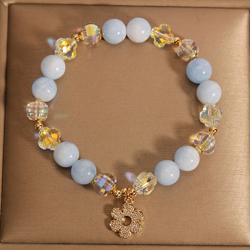 Women's adjustable bracelet with aquamarine crystal four-leaf clover charm and pearl detail.