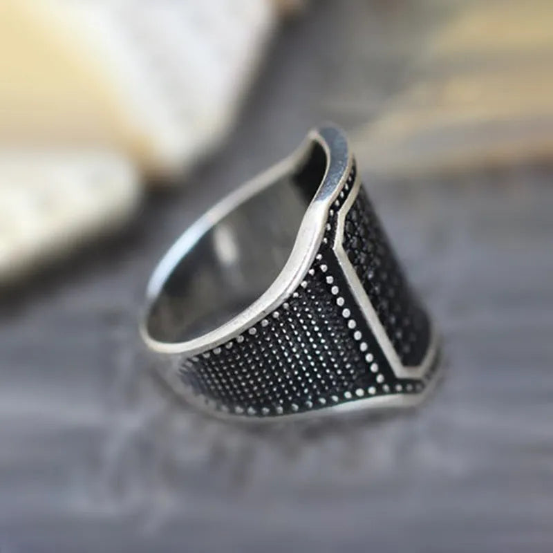 Black alloy ring with copper inlaid detail around a central zircon stone.