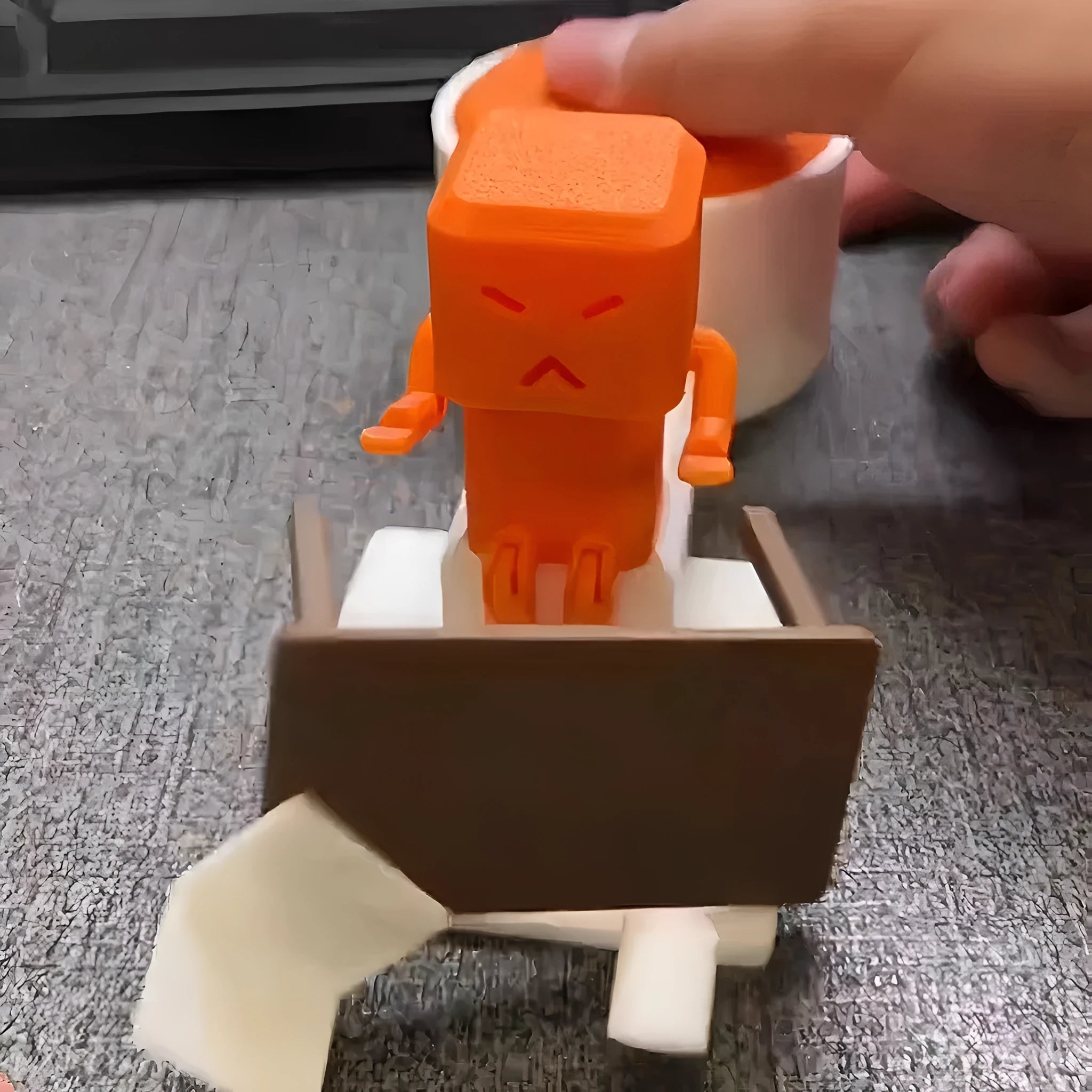 Orange plastic table-turning decompression toy measuring 16cm long on a desk