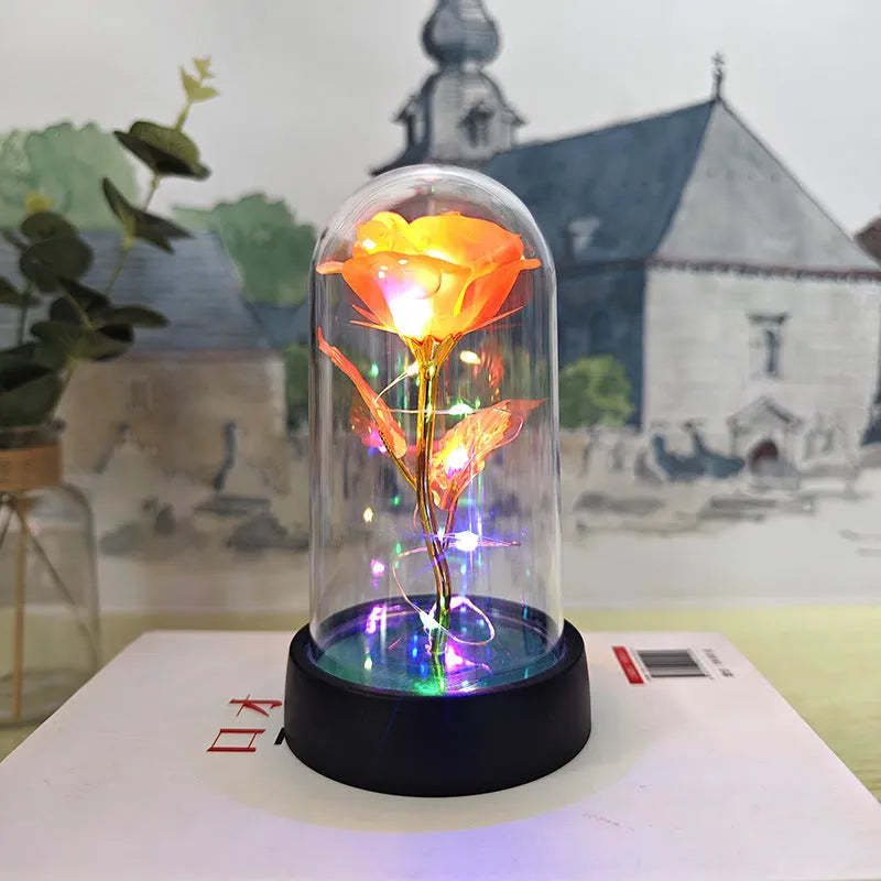 Small decorative night lamp with glass cover and plastic flowers, showing coloured light illumination.