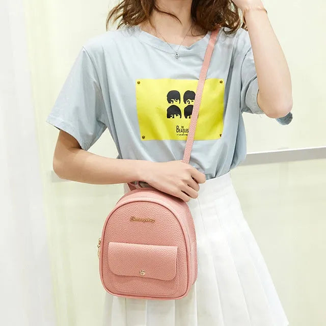 Women's small PU leather backpack shoulder bag in black showing front zipper and compact size