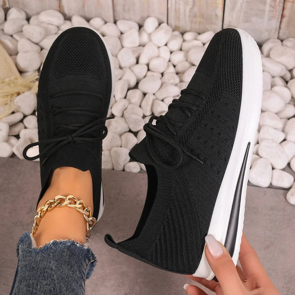 Women's black fly-knit casual sneakers with lace-up front and low-top design on a white background.