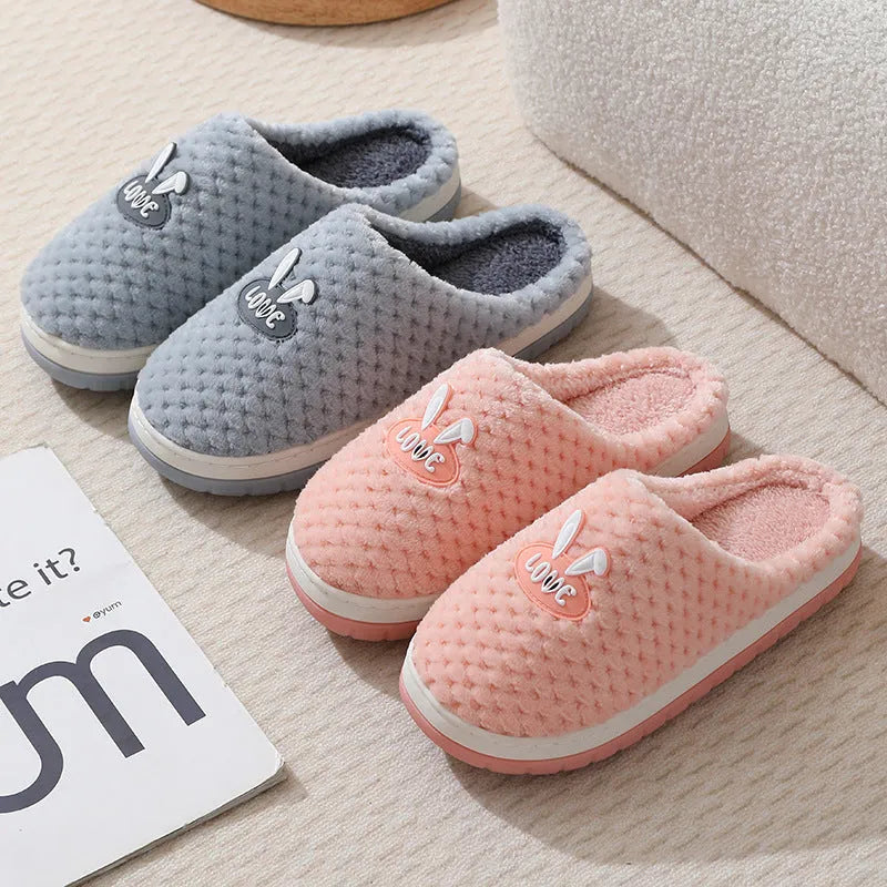 Women's plaid design artificial fur winter slippers with rubber sole on a wooden floor.