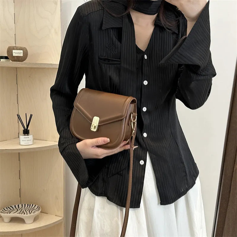 Men's soft black PU leather clamshell messenger bag in a horizontal square shape on a table.