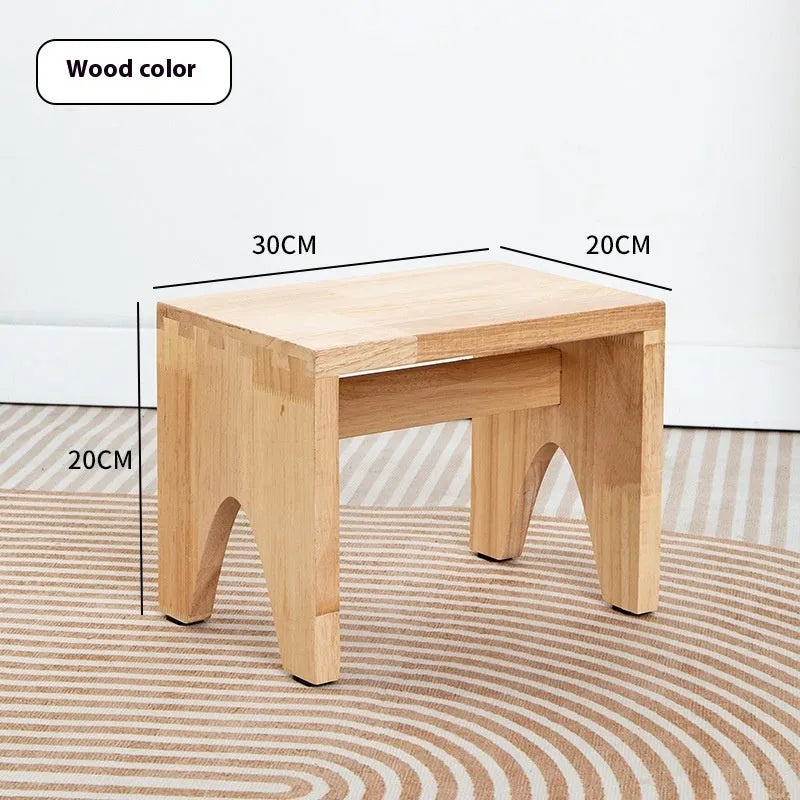 Solid wood changing stool with distressed finish and bracket legs in a living room setting.