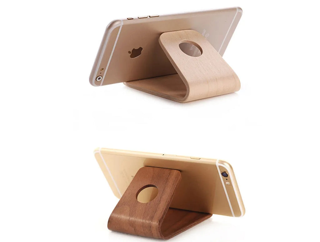 Wooden phone charging stand for iPhone in walnut or white maple finish on a desk.