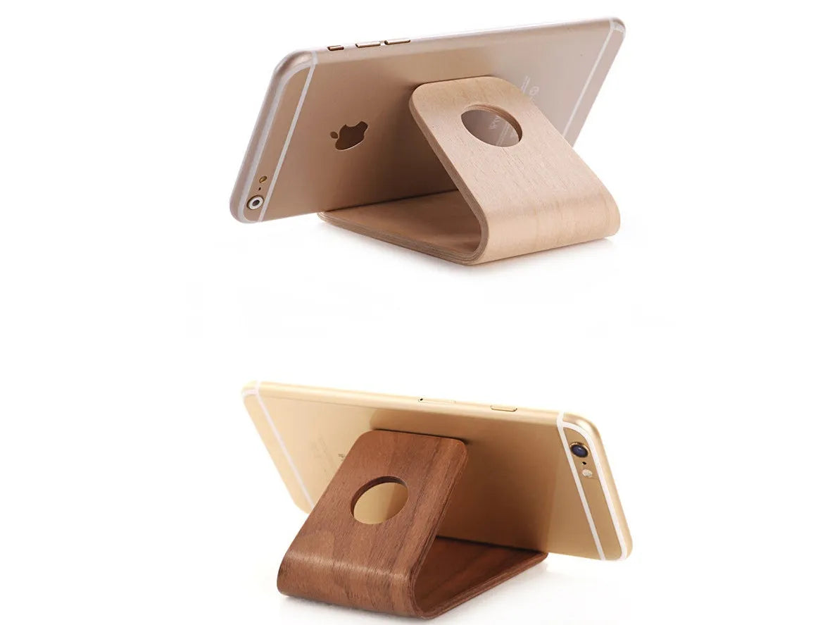 Wooden phone charging stand for iPhone in walnut or white maple finish on a desk.