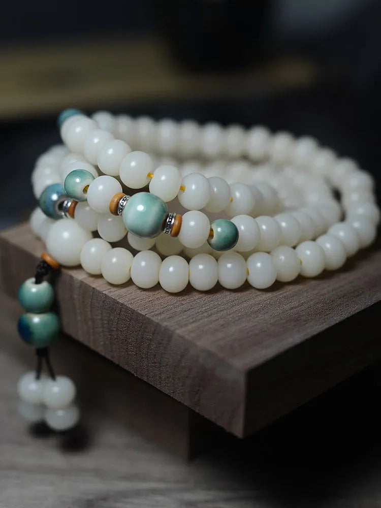 White jade bodhi seed bracelet with 108 flat round beads on a wrist.